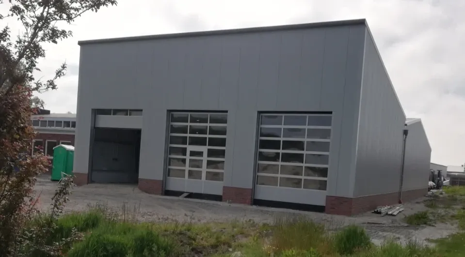 Ein großes Gebäude mit vielen Fenstern und einer grünen Mülltonne davor.