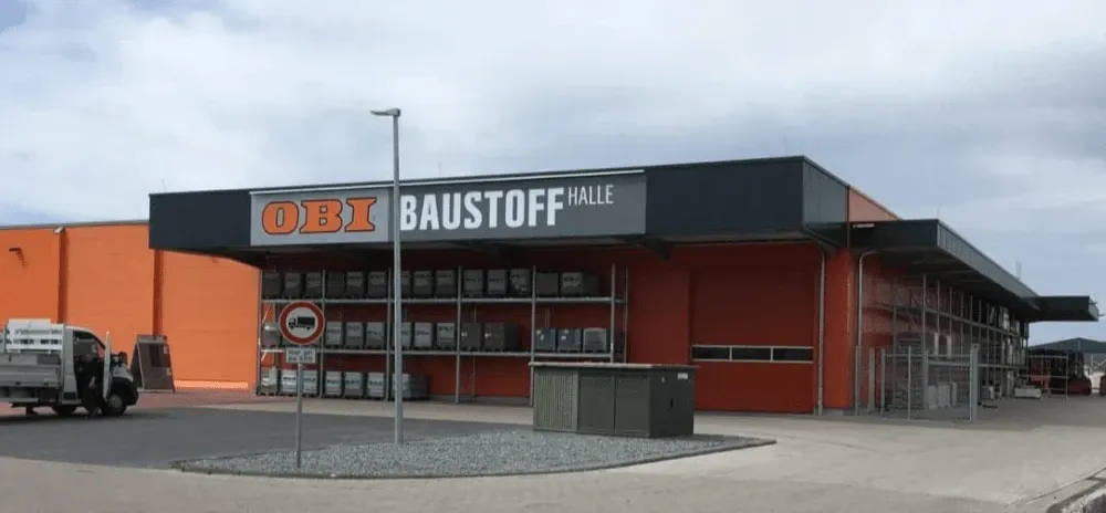 Ein großes orangefarbenes Gebäude mit einem Schild mit der Aufschrift „OBI Baustoff Halle“.