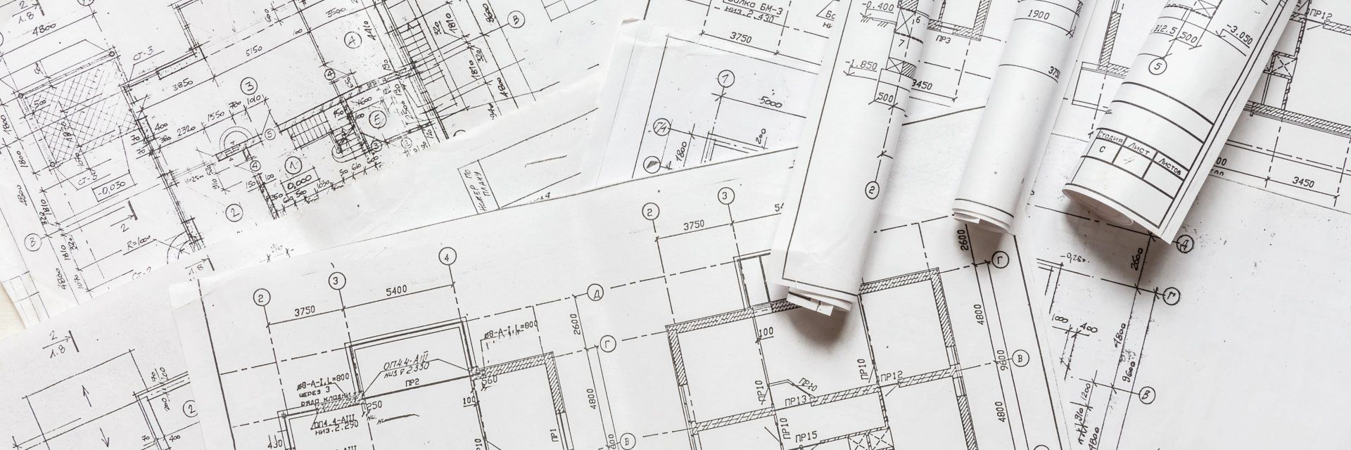 Ein Stapel Rollen mit Architekturzeichnungen auf einem Tisch.