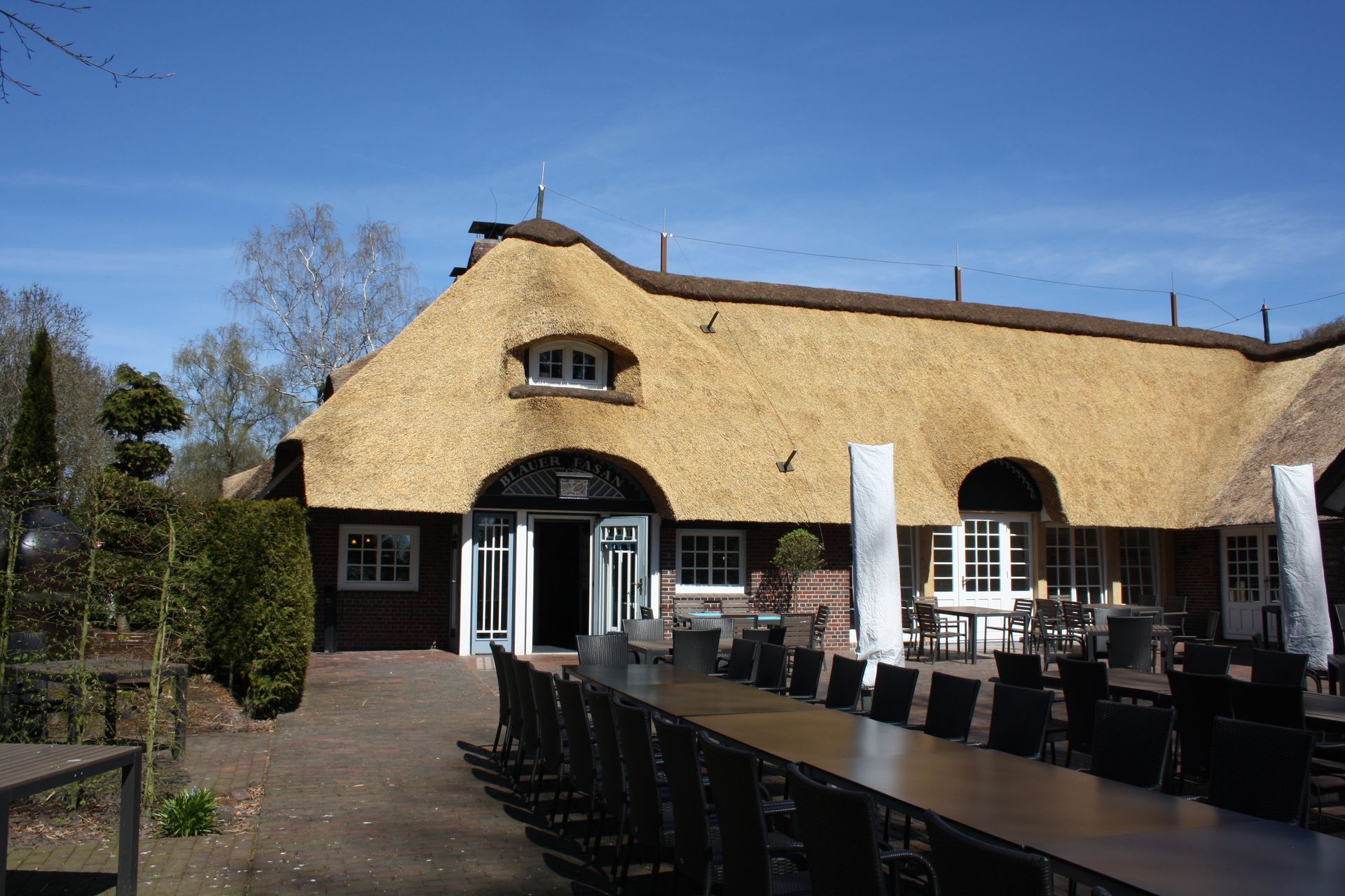 Ein strohgedecktes Gebäude mit einem langen Tisch und Stühlen davor.