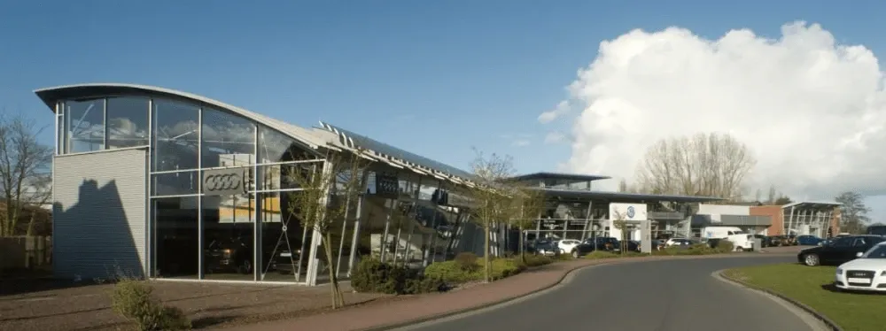 Ein großes Gebäude mit vielen Fenstern und davor geparkten Autos