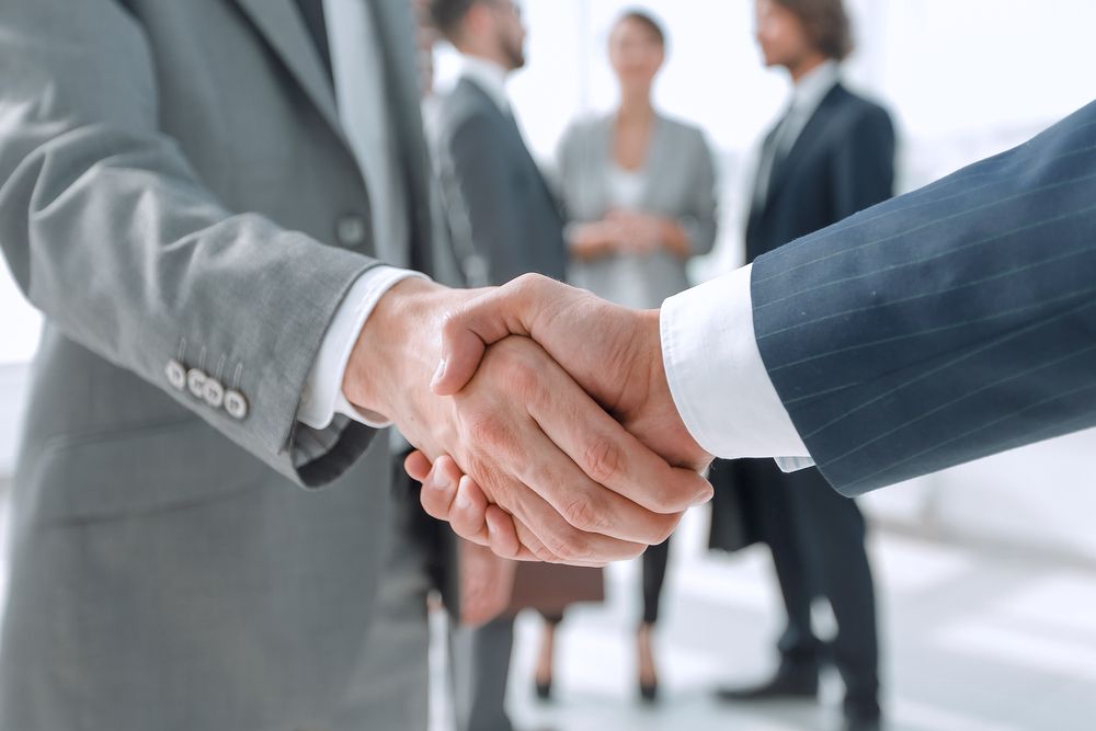 A group of business people are shaking hands in an office.