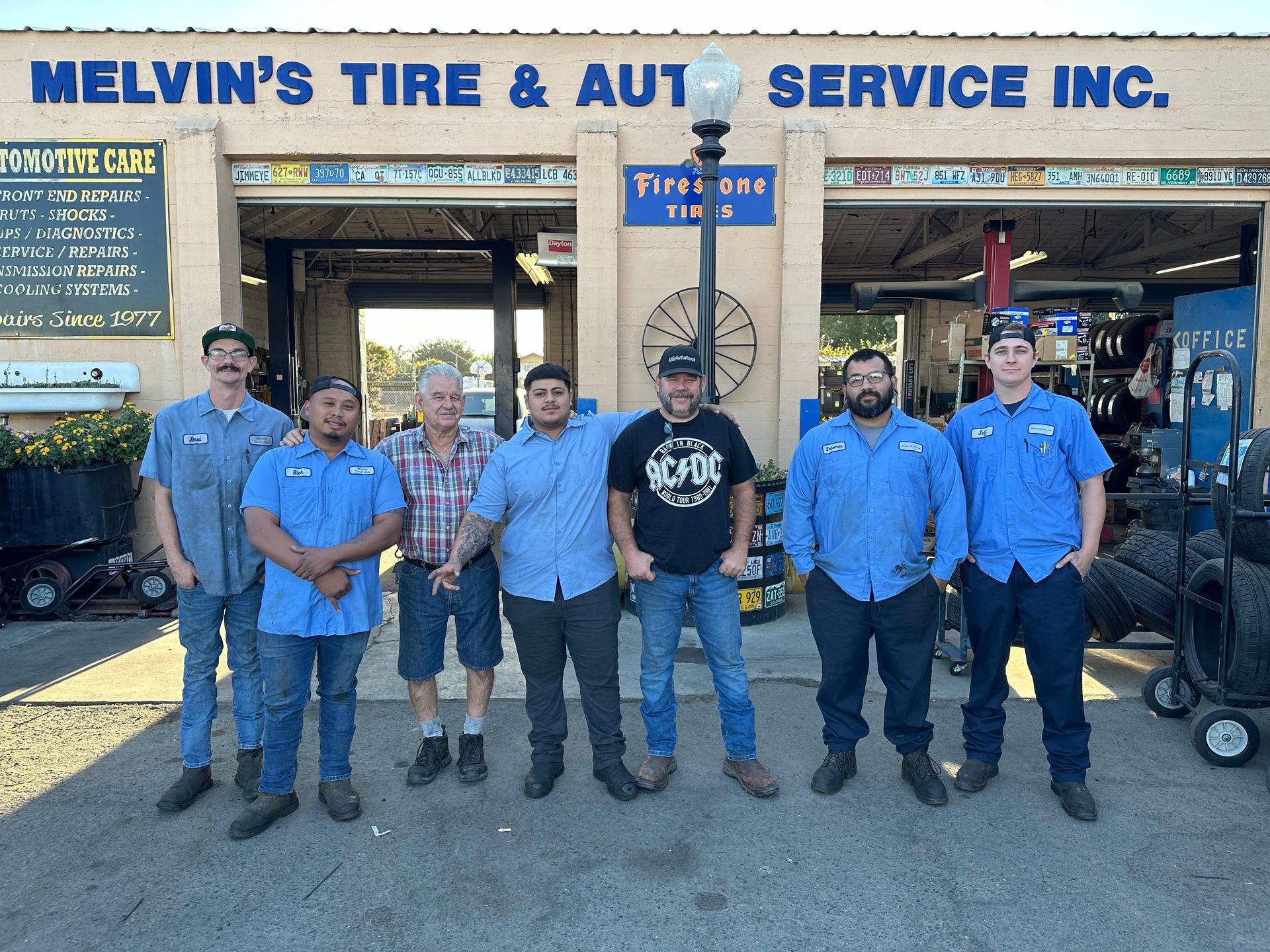 A group of men standing in front of a melvin 's tire and auto service inc.