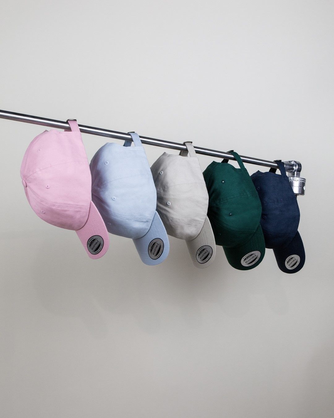 A bunch of baseball caps are hanging on a rack.