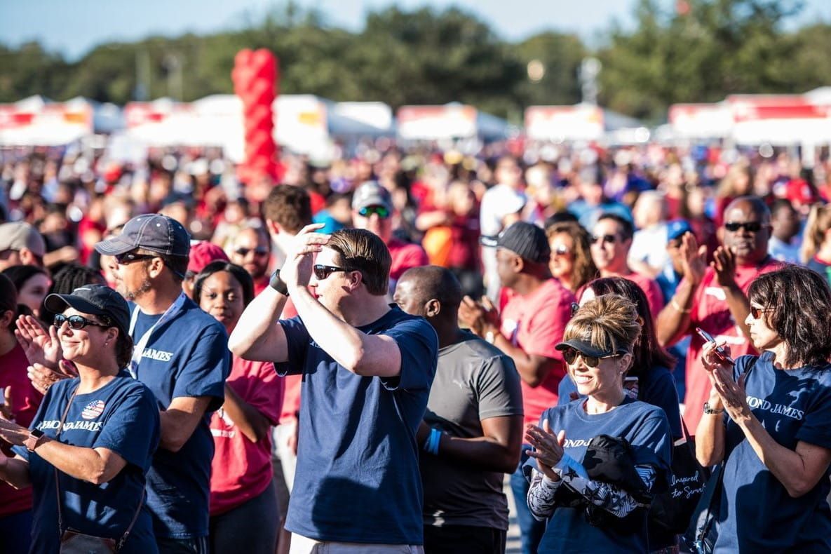 A large group of people are standing in a crowd and applauding.