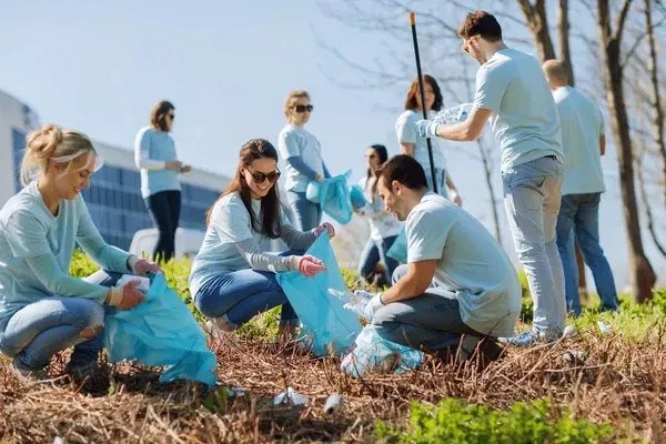 A group of people are picking up trash in a field.