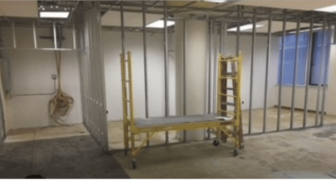 Construction site: Metal studs frame walls, a ladder, and a work platform inside a room.