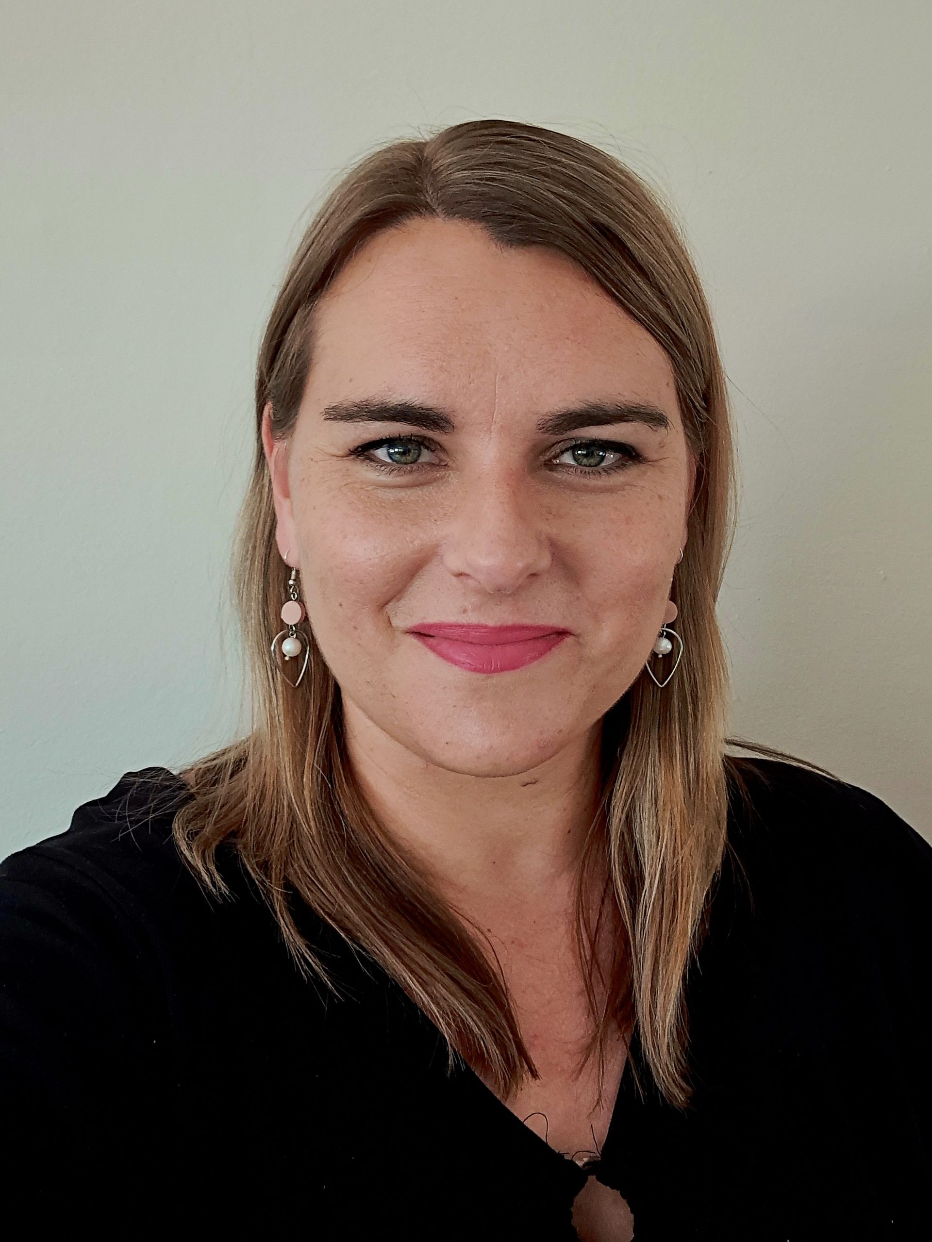 Portrait of a smiling woman with shoulder-length light brown hair against a plain light background