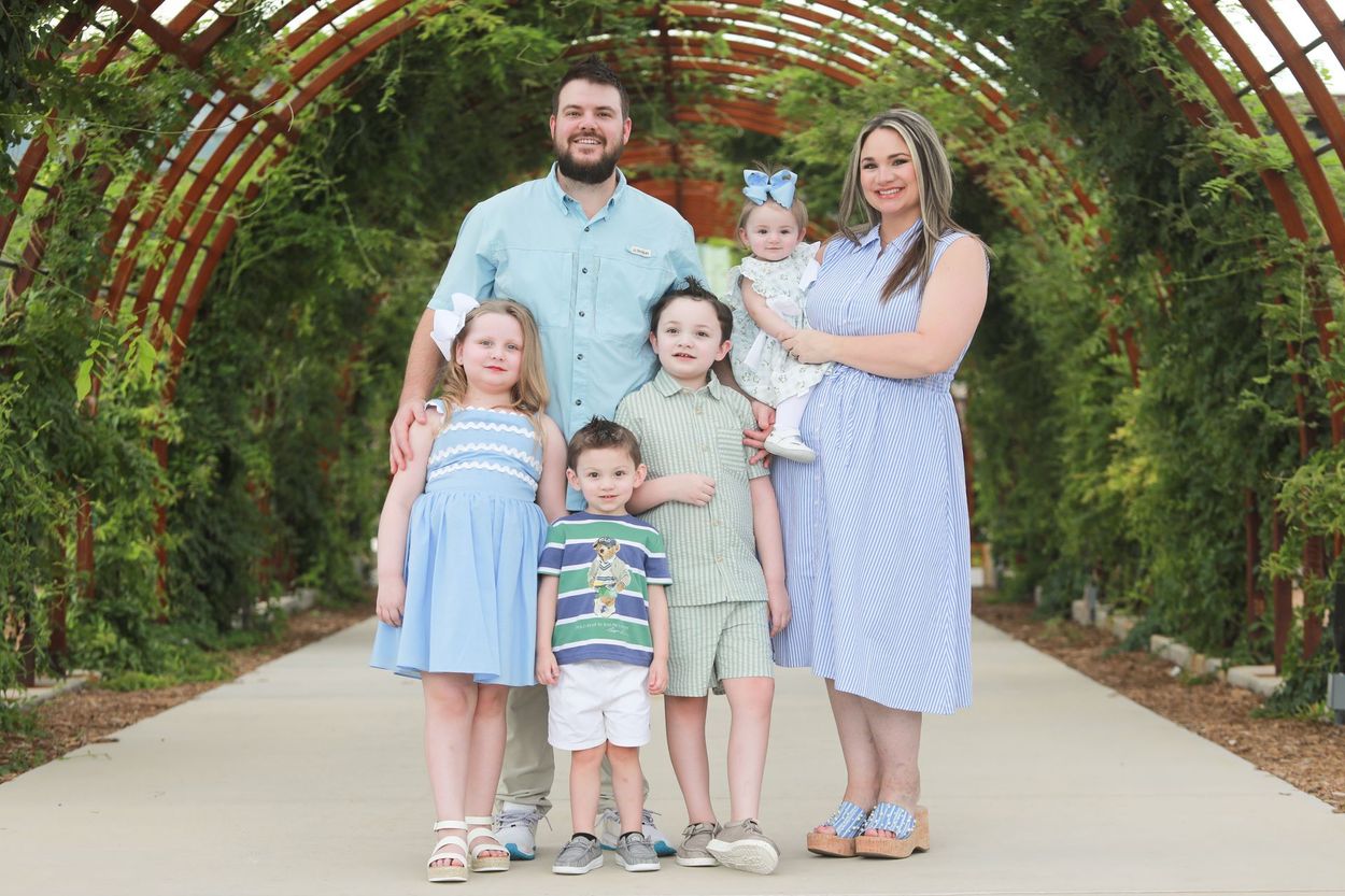 A family is posing for a picture in front of a wooden archway.