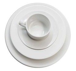 White cup and saucer on stacked white plates, viewed from above