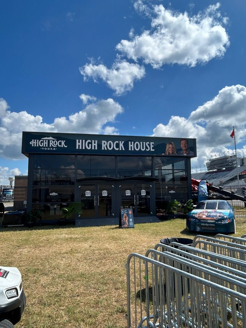 High Rock House event tent with cars, metal barriers, and a blue sky on a sunny day