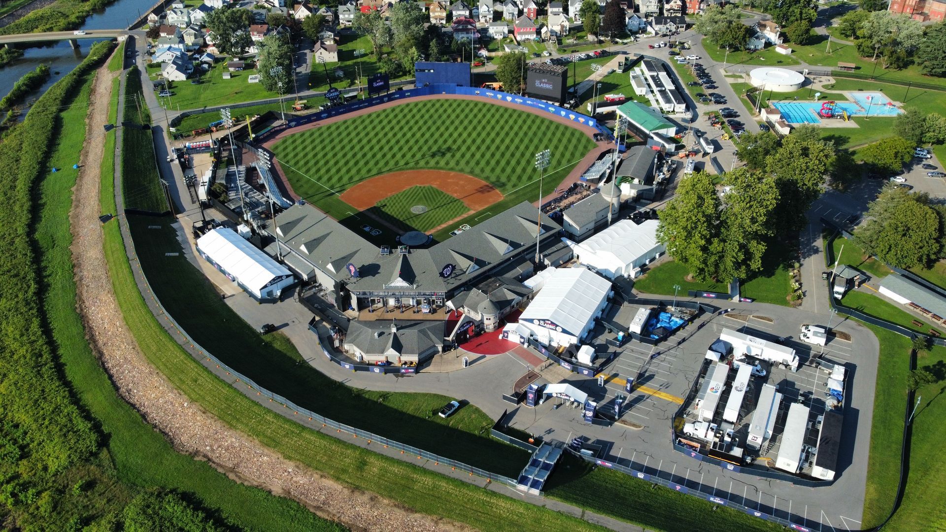 Aerial view of a baseball stadium with a green field, red infield, and surrounding parking lots and buildings