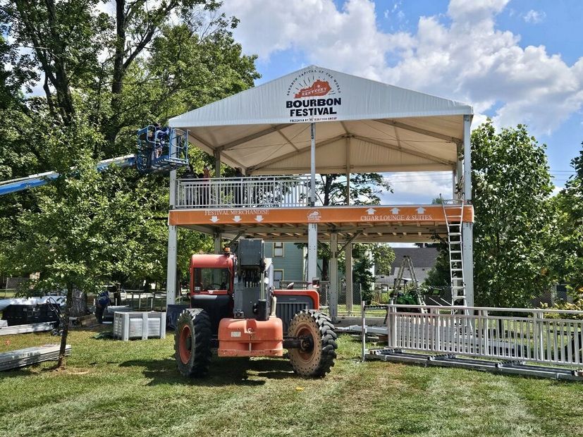 Louisiana festival entrance with orange tractor beneath a white canopy and blue sky