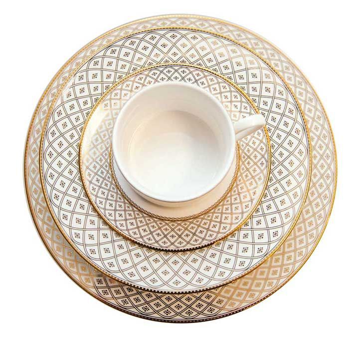 White teacup on a gold-and-white patterned saucer, viewed from above.