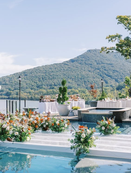 Poolside terrace with white flowers, a mountain view, and a turquoise pool under a clear sky