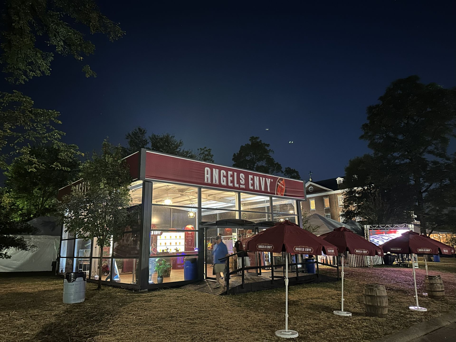 Nighttime outdoor dining at a lit restaurant with red umbrellas and a sign reading “Hacienda.”