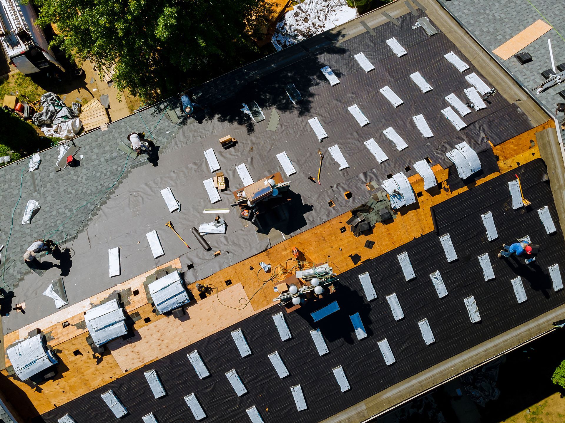 Aerial view of pedestrians crossing a street at a diagonal crosswalk with orange lane markings and cars nearby