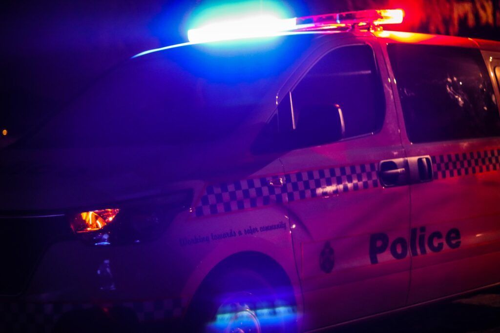 Police car at night with flashing red and blue lights.