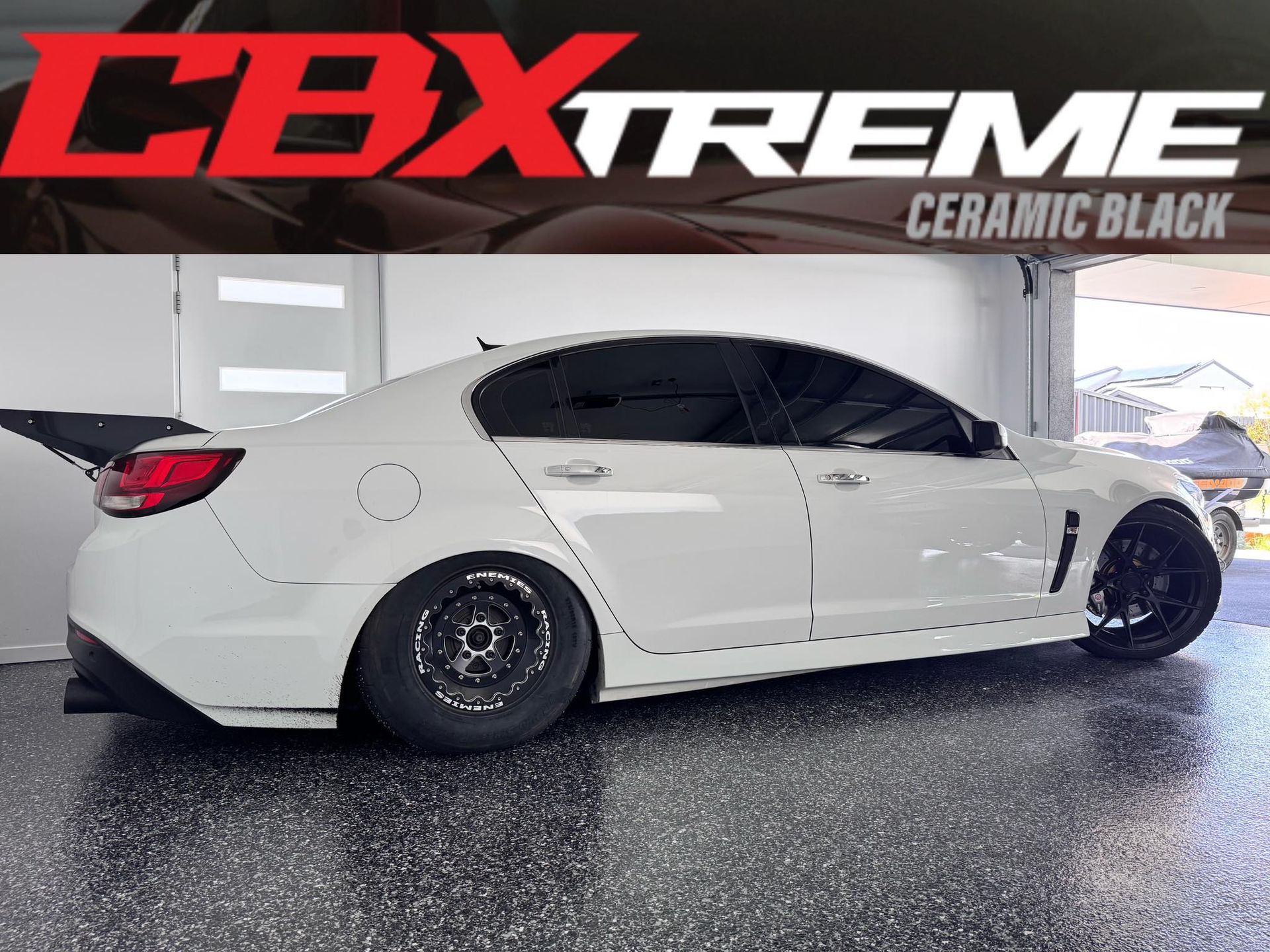 White sedan with black wheels in a garage, overlaid with “CBXtreme Ceramic Black” text
