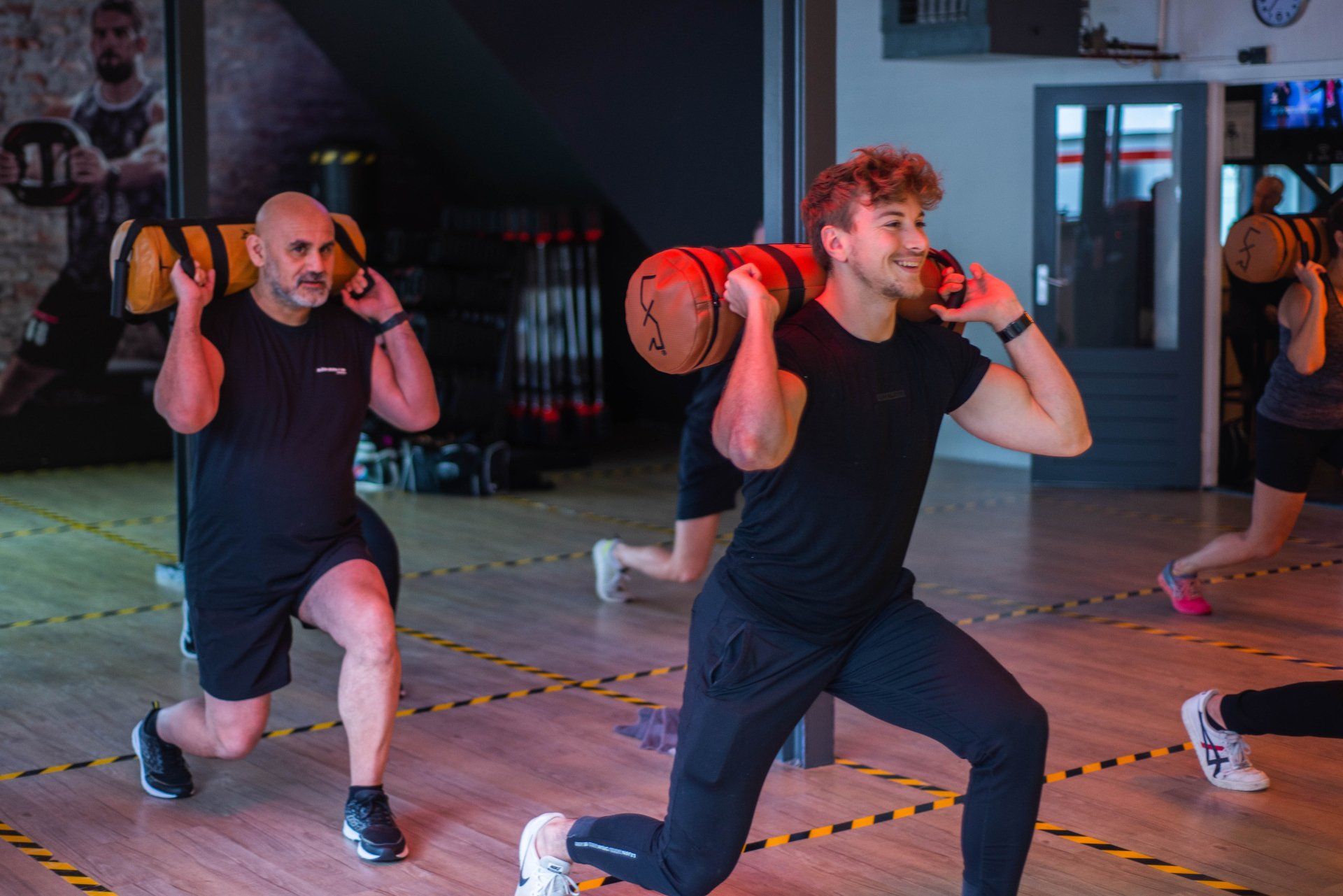 2 Mannen doen lunges met gewichten in een sportschool.