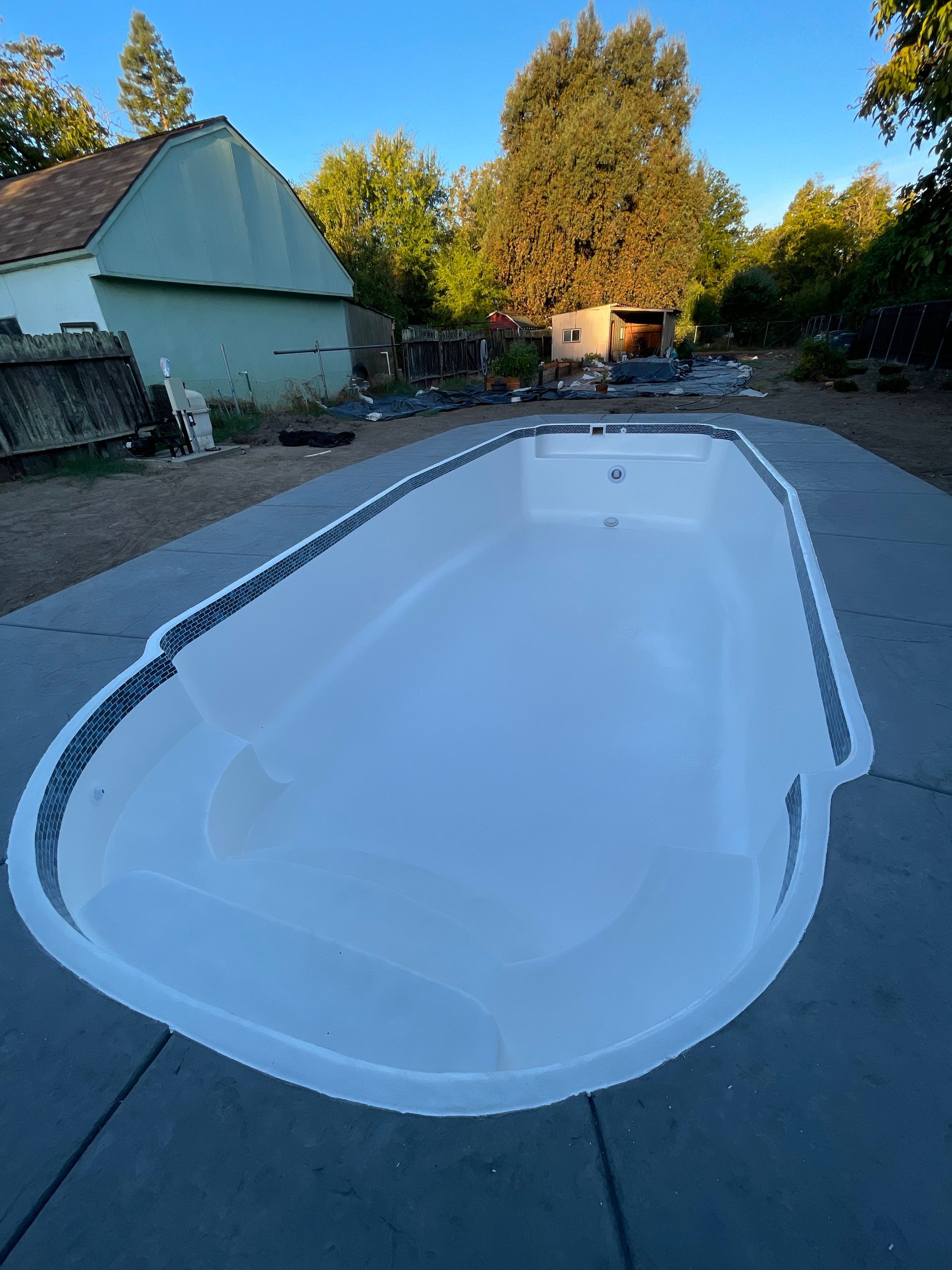 Empty white swimming pool, oval shape, set in concrete, outdoor setting. Empty white swimming pool, oval shape, set in concrete, outdoor setting.