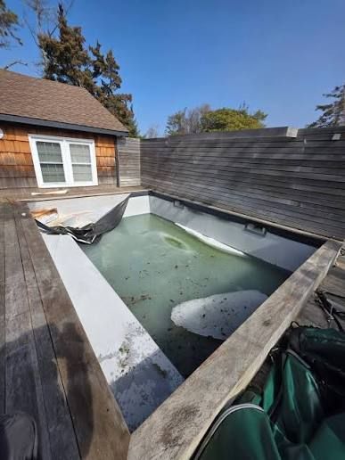 Pool with curved edges, blue water, stainless steel ladder, white coping, and concrete patio. Pool with curved edges, blue water, stainless steel ladder, white coping, and concrete patio.