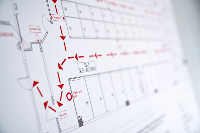 A close up of a floor plan of a building with red arrows pointing in different directions.