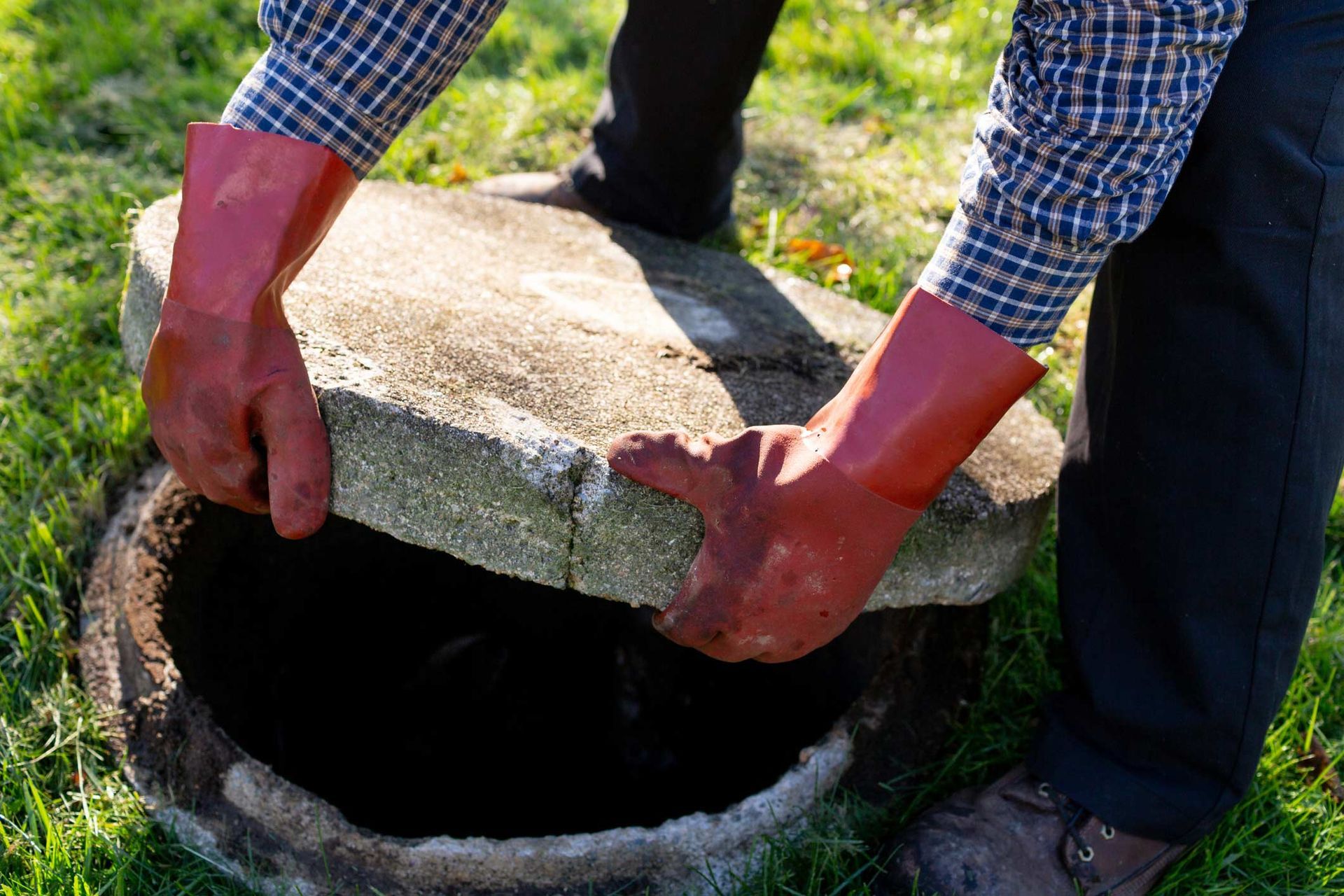 Plumber In Gloves Lifting Up Cover Of Septic Tank — Little Valley, NY — TRI R SERVICES Plumber In Gloves Lifting Up Cover Of Septic Tank — Little Valley, NY — TRI R SERVICES