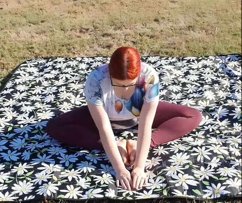 A Woman is Sitting on a Blanket With Daisies on It — Anderson Family Chiropractic Health Centre in Mount Pleasant, QLD