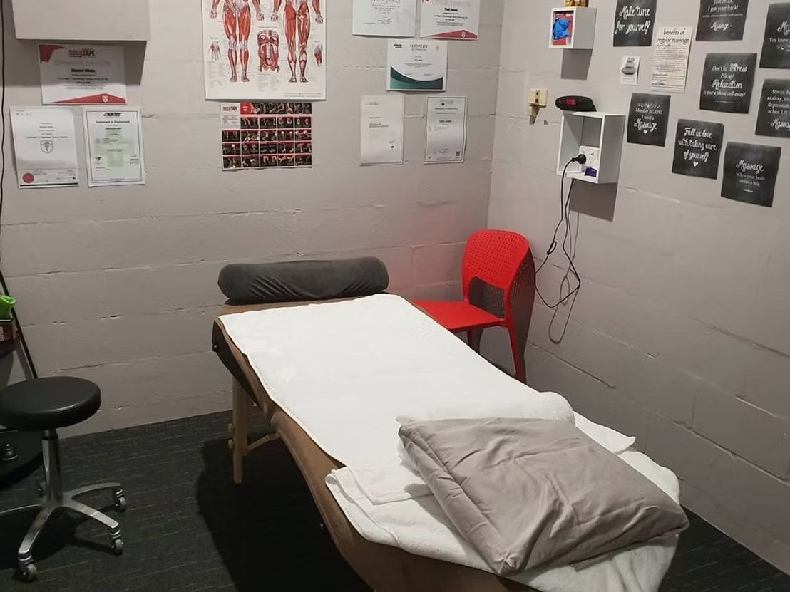 A Massage Table in a Room With Posters on the Wall — Anderson Family Chiropractic Health Centre in Mount Pleasant, QLD