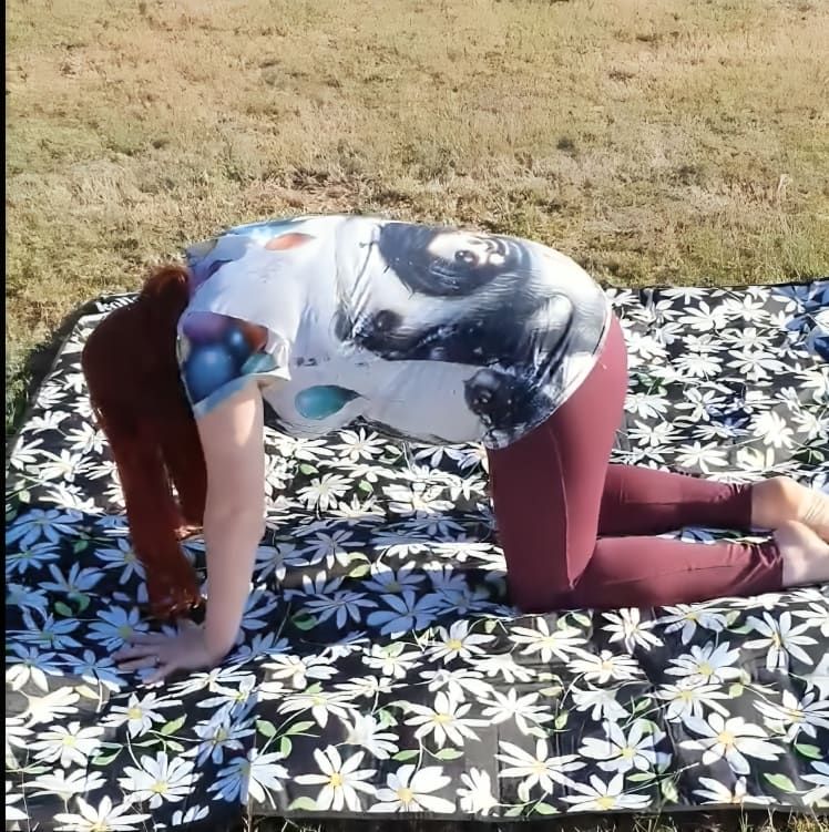 A Woman is Kneeling on a Blanket With Daisies on It — Anderson Family Chiropractic Health Centre in Mount Pleasant, QLD