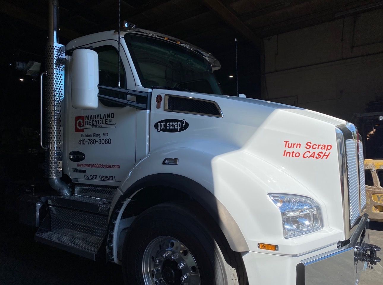 A white Kenworth semi-truck parked indoors, featuring red 