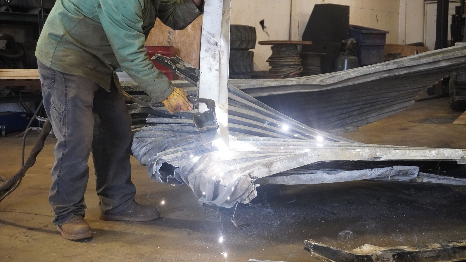 Worker welding a metal frame, sparks flying in a workshop.