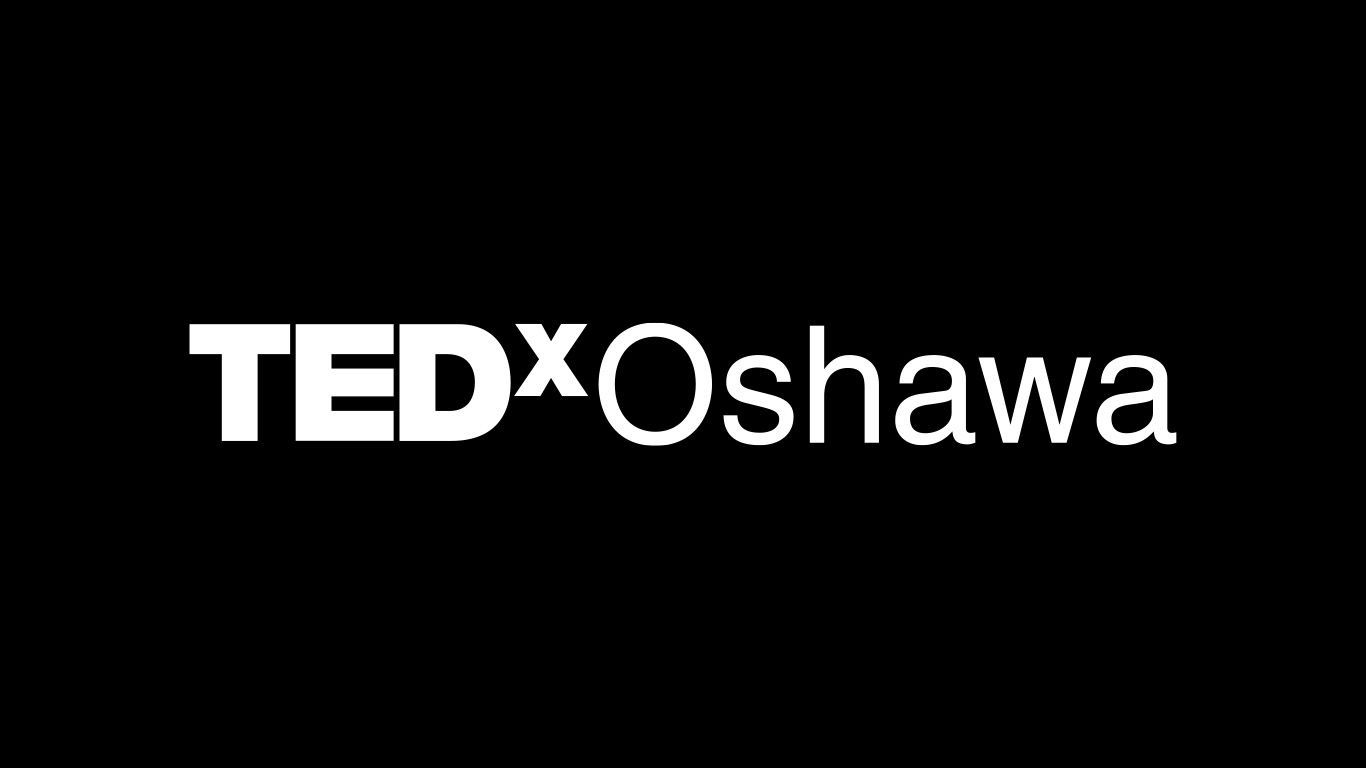 TEDxOshawa stage with a Constantine Karbaliotis on a red circular platform beside the illuminated TEDxOshawa sign