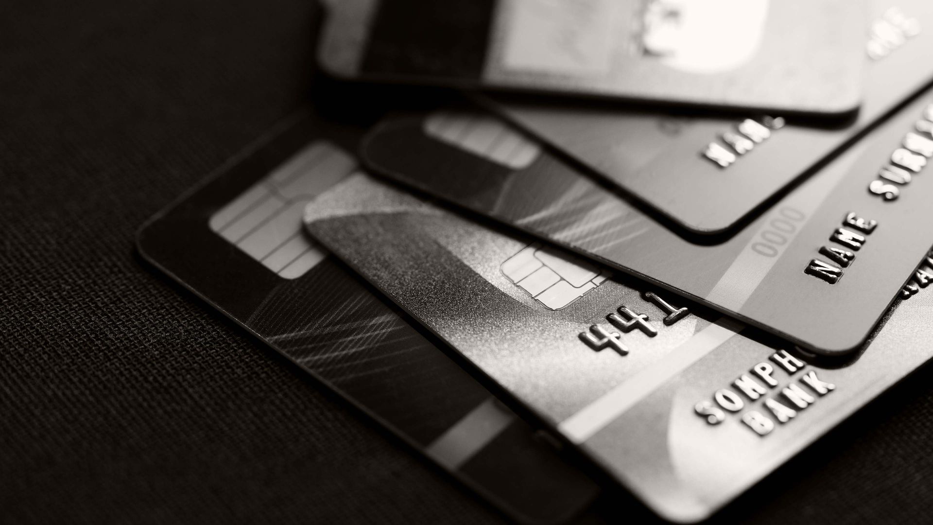 Stack of black and silver credit cards on a dark surface