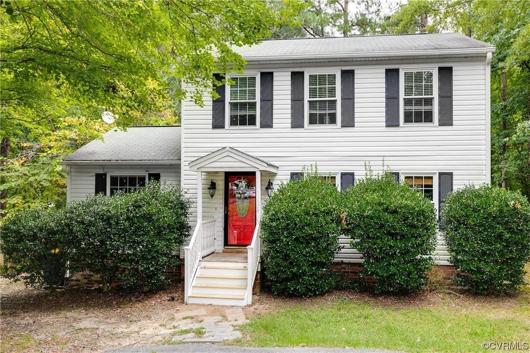 a white house with black shutters and a red door