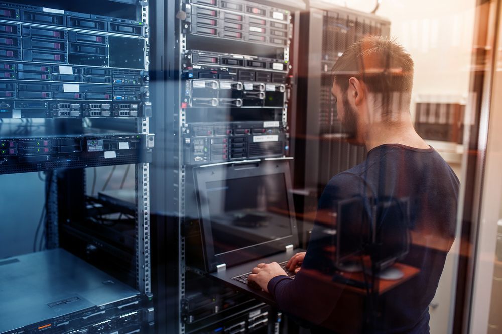 A Man is Working on a Laptop in a Server Room — Complete Computing Consultancy In Hervey Bay, QLD