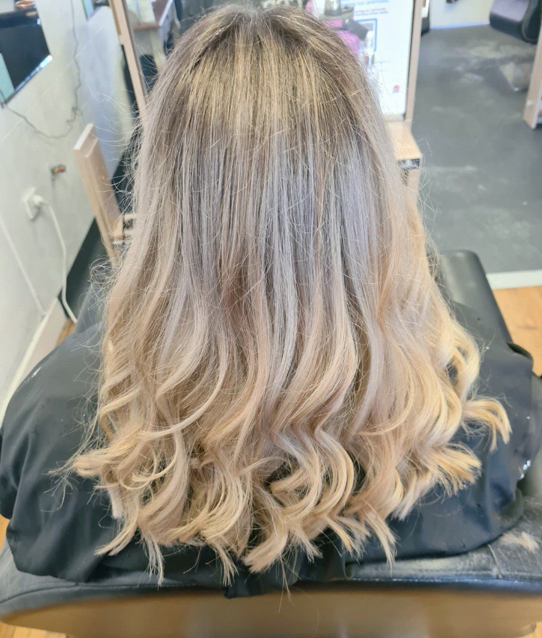 A woman is sitting in a chair with her hair in a salon.