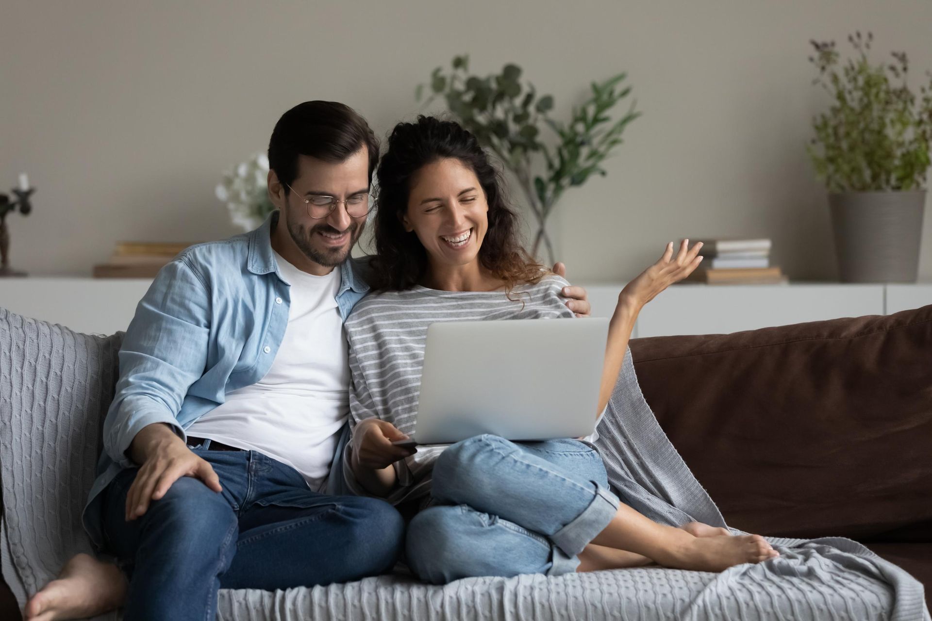 Smiling couple on a couch using a laptop in a cozy living room