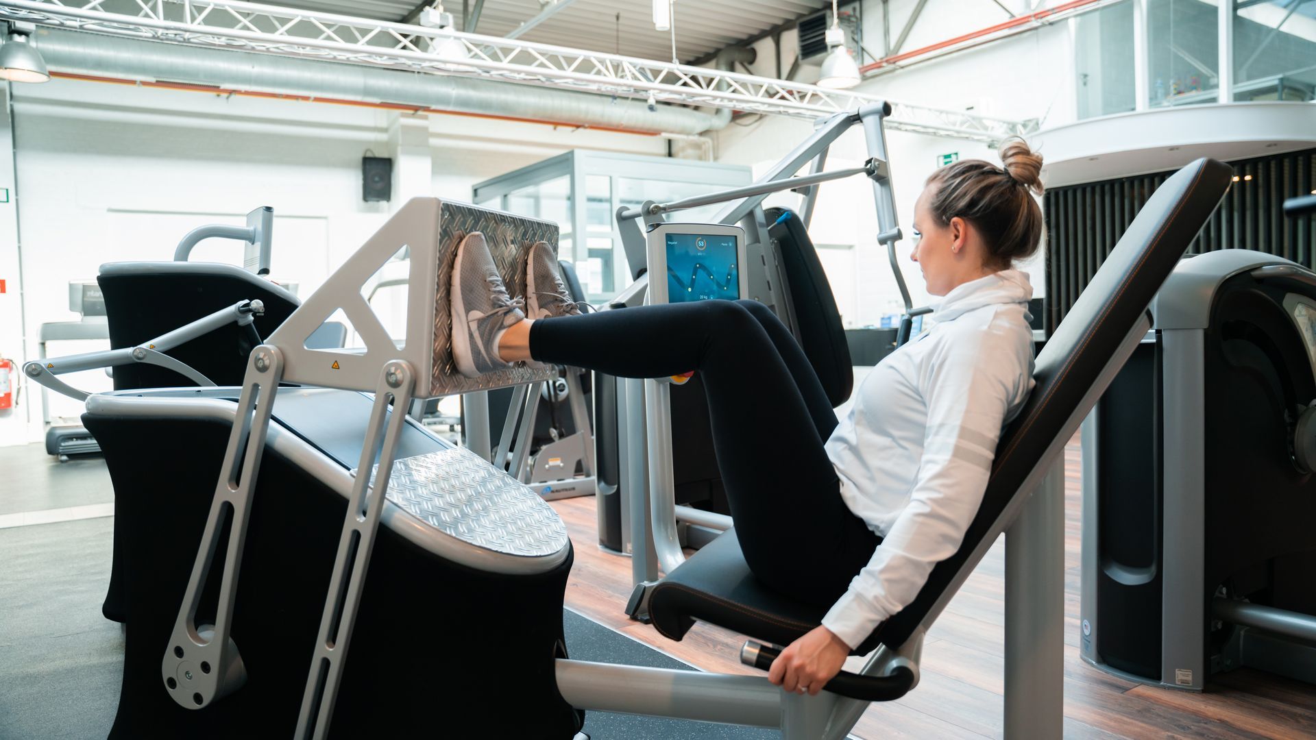 Een vrouw gebruikt een leg press-apparaat in een sportschool.