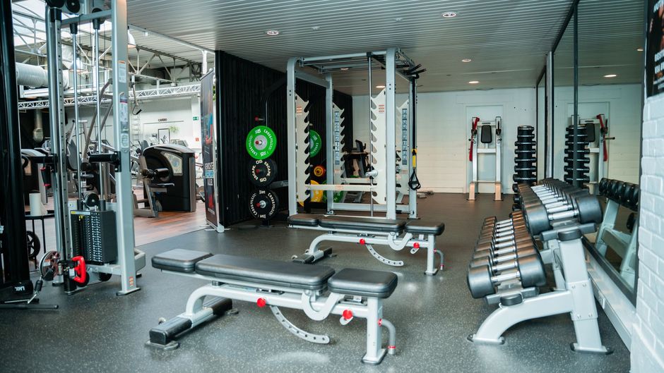Een man tilt een halter op een bankje in een sportschool.