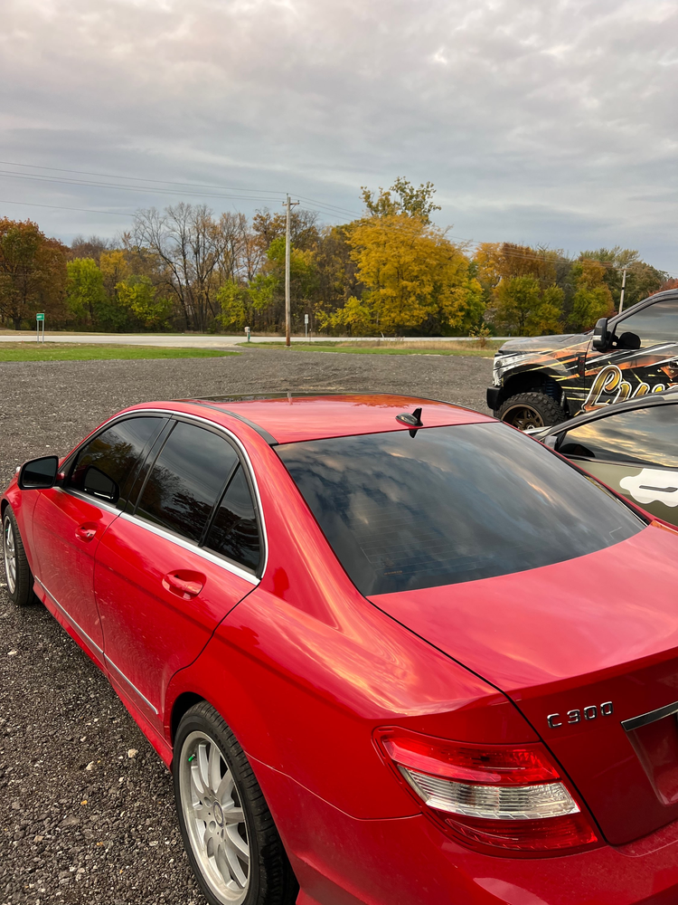 A red car is parked in a parking lot next to a truck.