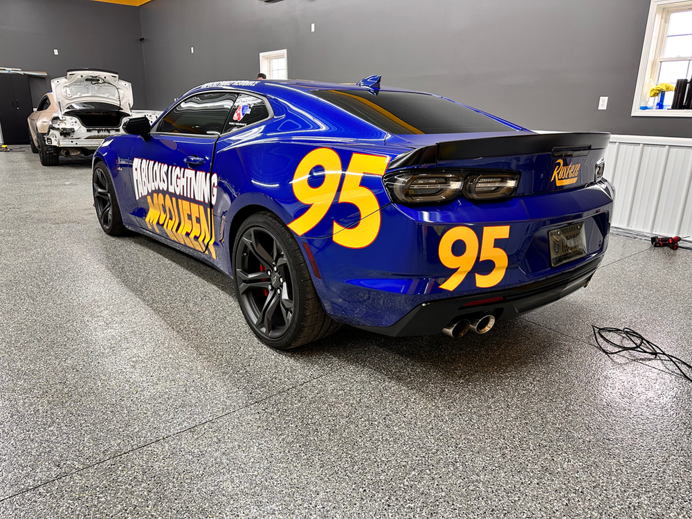 A blue race car with the number 95 on the back is parked in a garage.