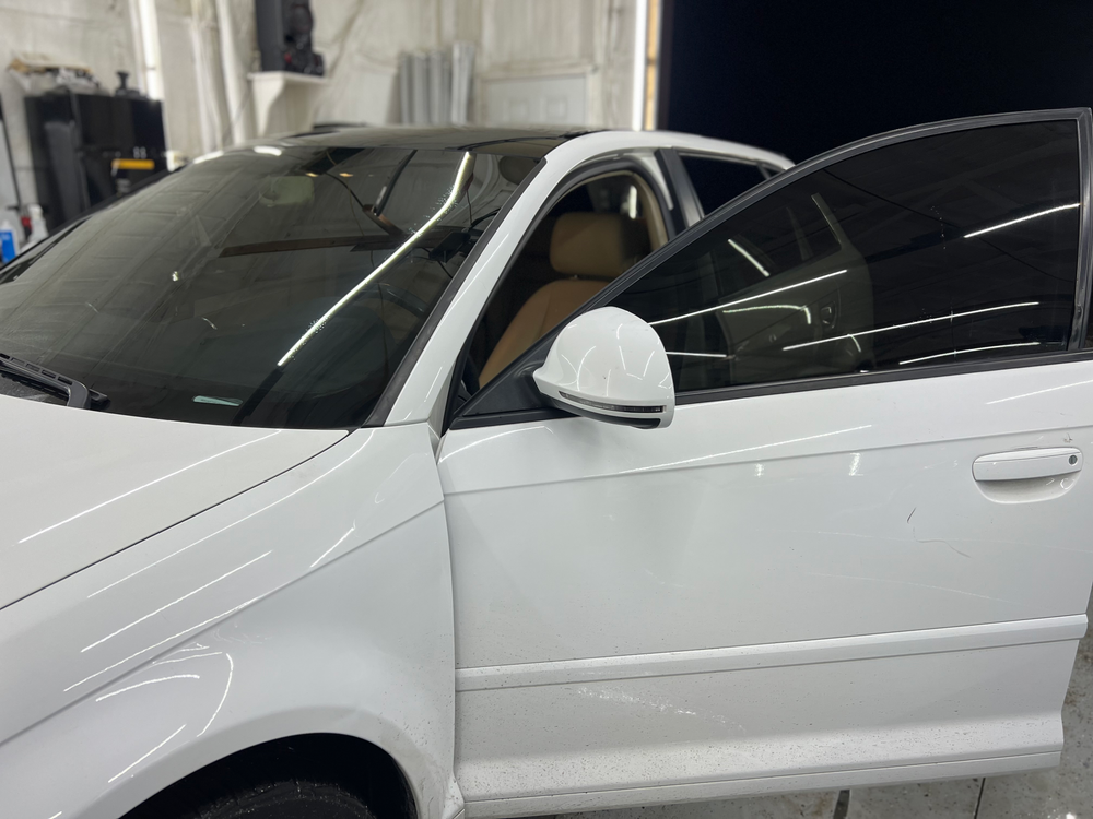 A white car with black windows is parked in a garage.