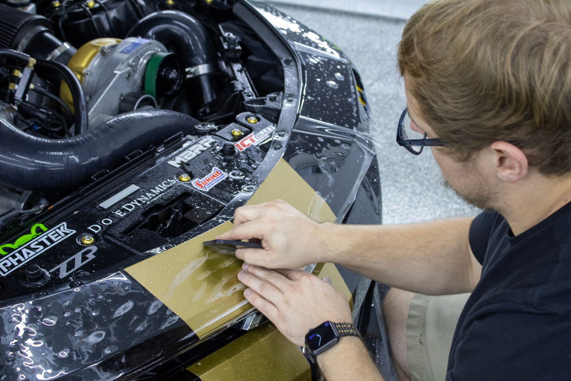 A man is applying protective film to the hood of a car.