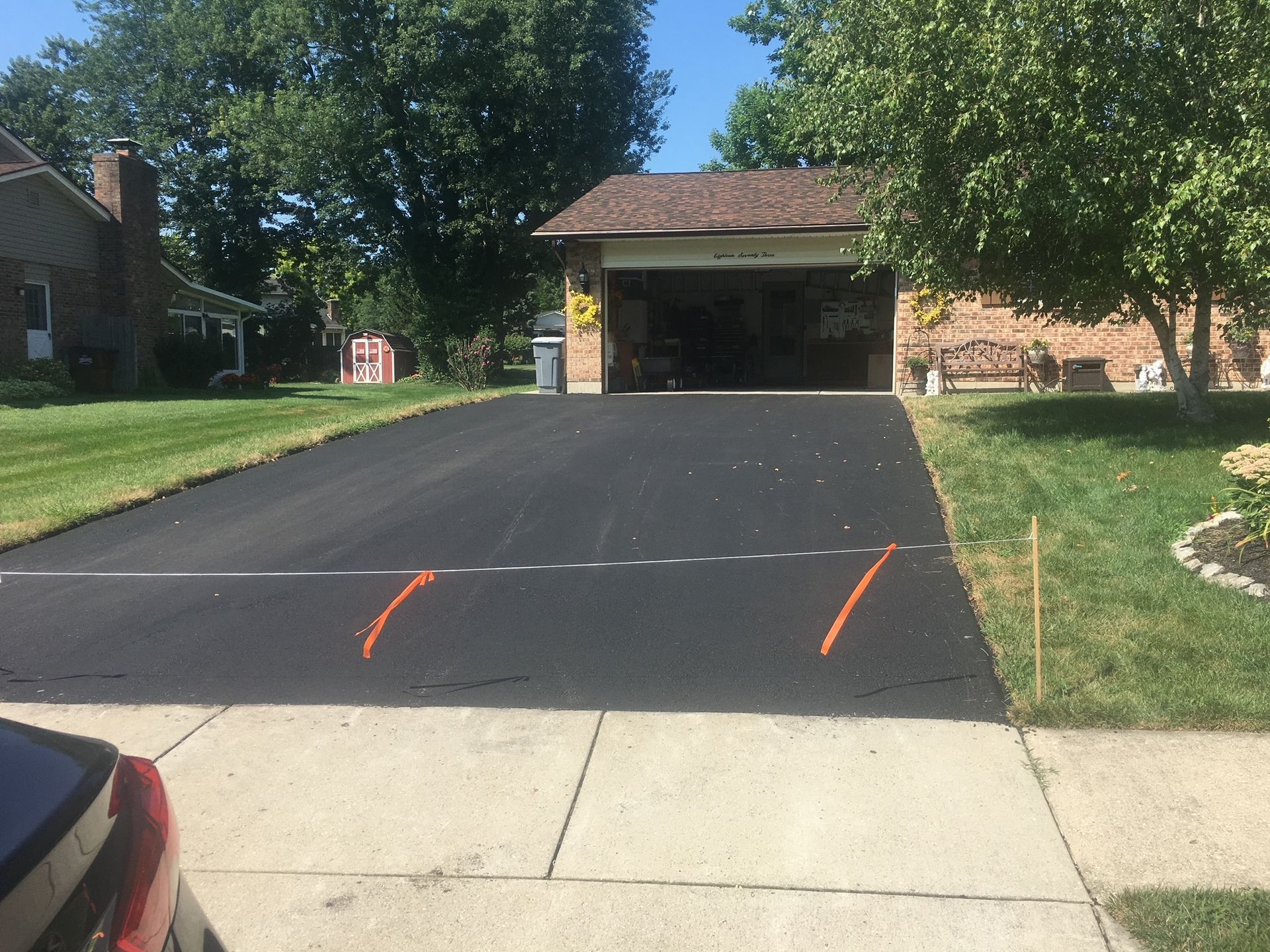 Fresh black driveway in front of a garage, with orange marking lines near the curb.