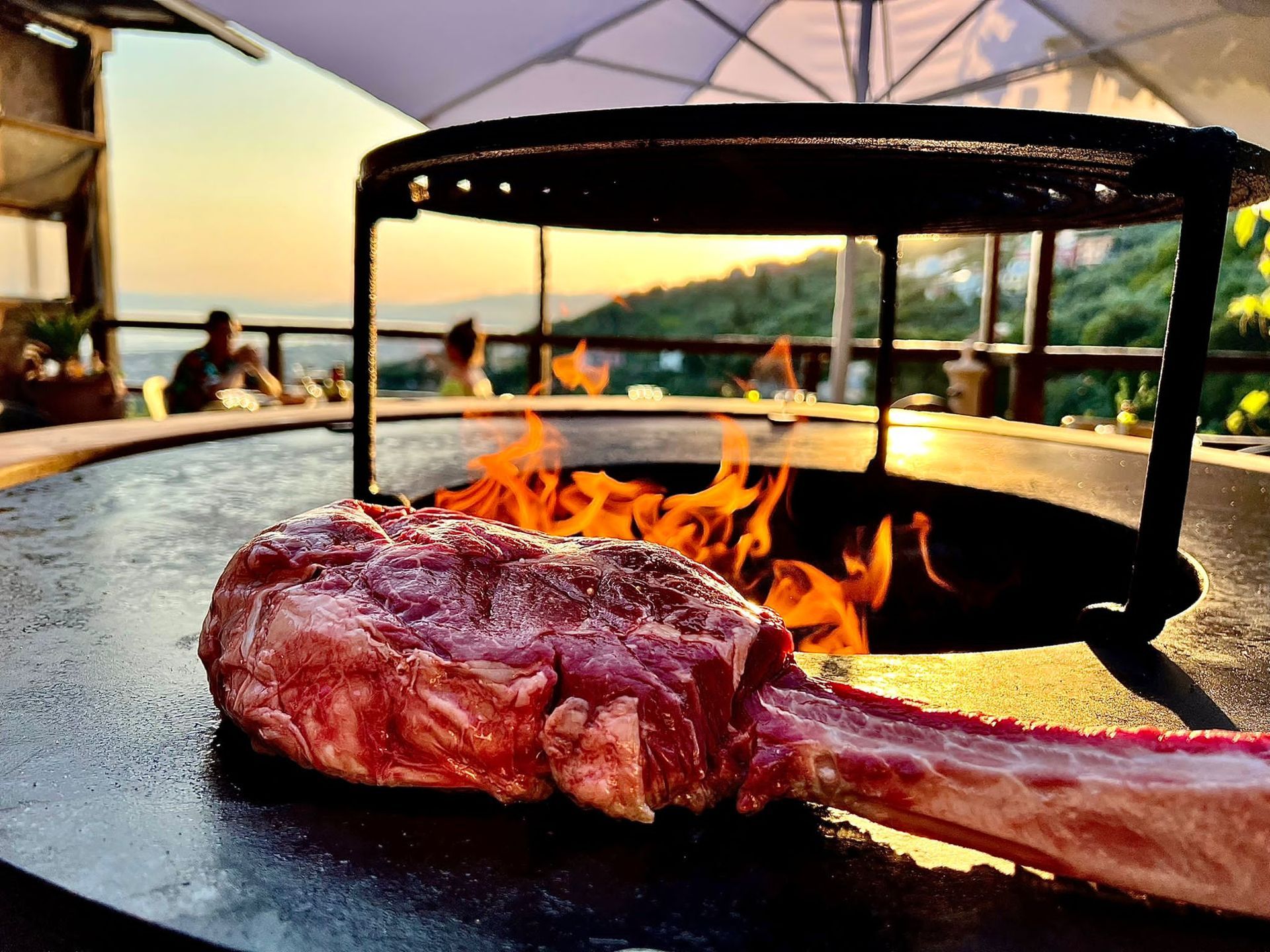 Una grande bistecca tomahawk cotta su una griglia con fiamme, scena di cena all'aperto.