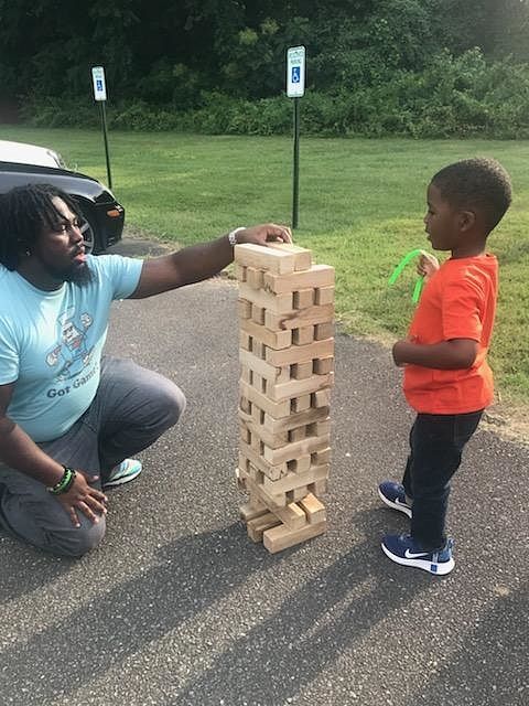 A man and a boy are playing a game of jenga at a LCRC community event.