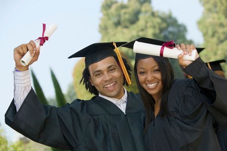 Young man and a woman are holding their diplomas over their heads.