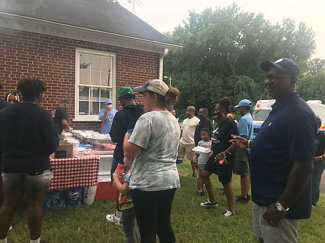 A group of people are standing in front of a brick building at a LCRC community event.